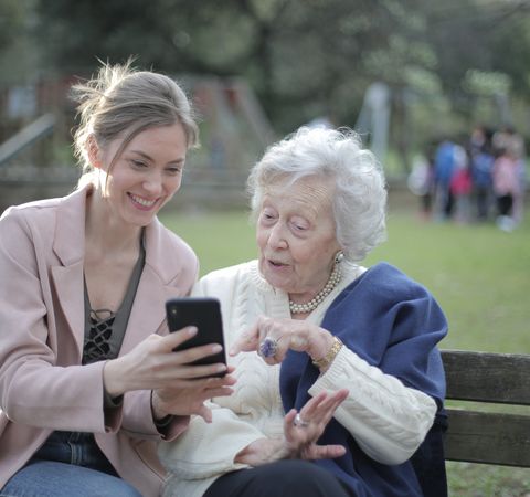 Frau zeigt Seniorin Smartphone