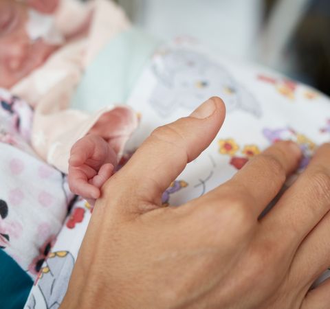 Frühgeborenes hält Hand von Mutter